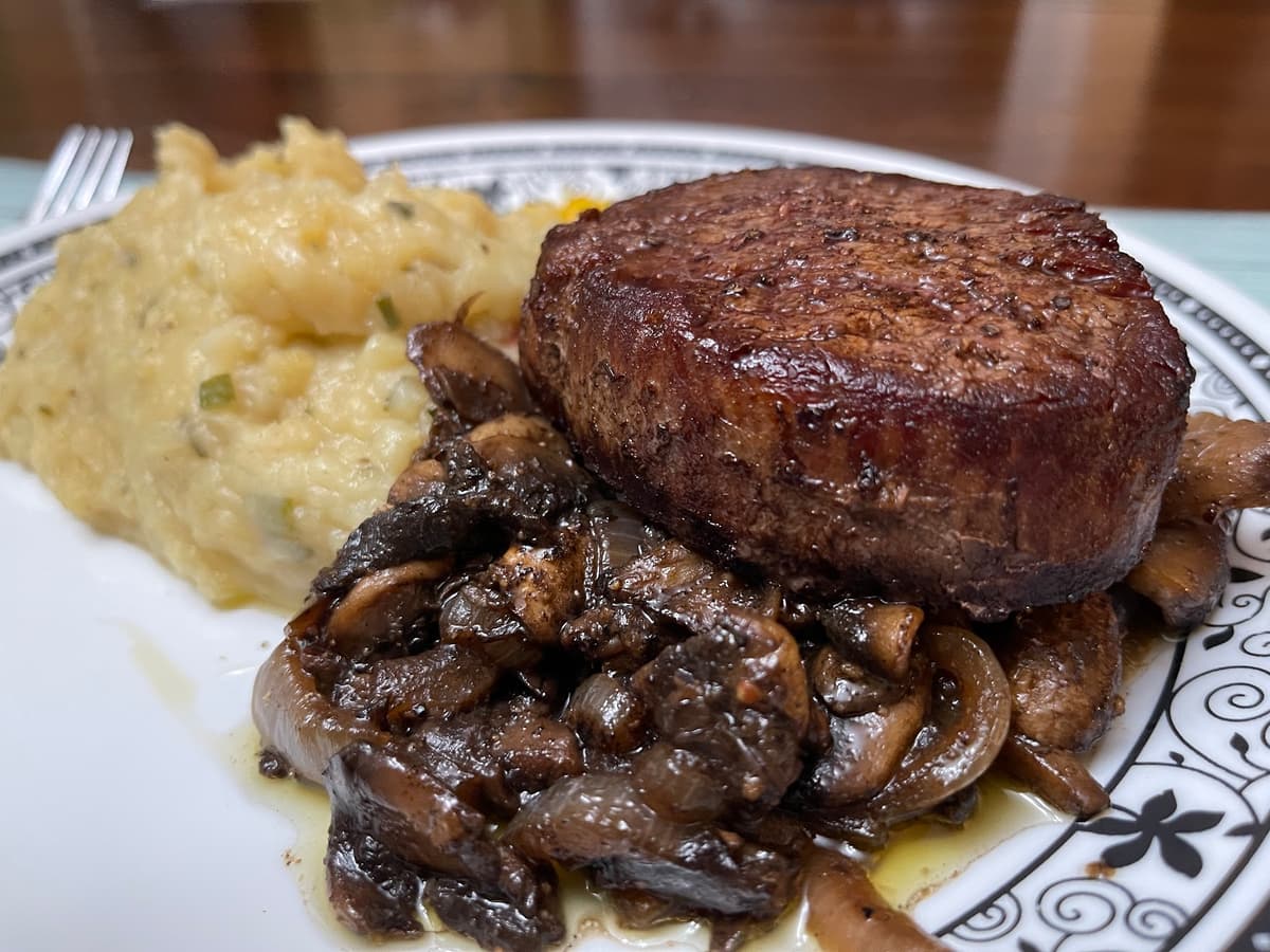 steak over mushrooms with a cheesey pasta